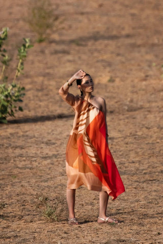 Front view of brown and orange one-side off-shoulder dress with single sleeve, featuring abstract prints designed in-house, crafted in plant-based Japanese fabric for modern occasion and summer styling. Designed by Clos.