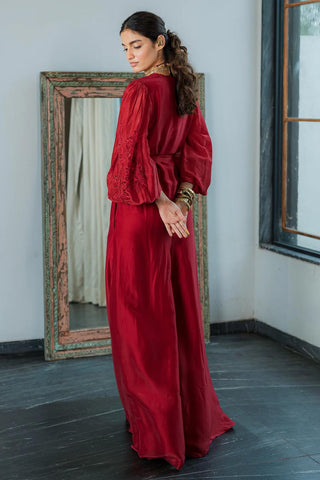 Back look of cherry red silk organza jumpsuit with intricate floral embroidery with deep v-neck and voluminous sleeves , styled for a formal evening party, cocktail parties, brunch to soiree. Designer women's outfit.