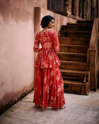 Back look of the crimson red peplum featuring Roop flip bird print. The yoke and sleeves are hand-embroidered and the peplum has drawstring detailing with delicate tassels. It is paired with printed palazzos. Perfect outfit for cocktail and special occasion.