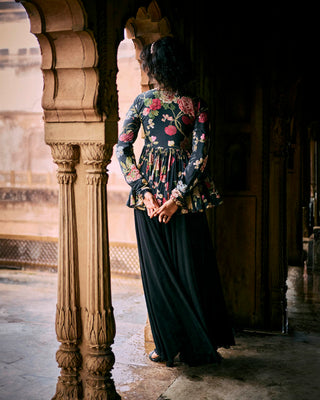 Back look of black floral printed peplum, featuring a hand-embroidered yoke and sleeves with drawstring and tassel detailing. It is paired with solid palazzos. Perfect traditional women's wear for special occasions, cocktail parties, wedding for brides and guests. 