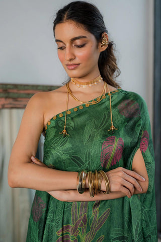 Close up of emerald green printed one shoulder dress with coin detailing on the neck, paired with straight cut trousers.  Resort wear, brunch to soiree, vacation in style, gen-z glam. 