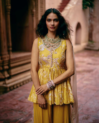 Close up of tuscany yellow peplum set Wedding Festivities, Day Outings, Cultural Events. It has intricate hand embroidery on the front and back of the yoke, with hand-embroidered lace detailing. It is paired with solid palazzos.