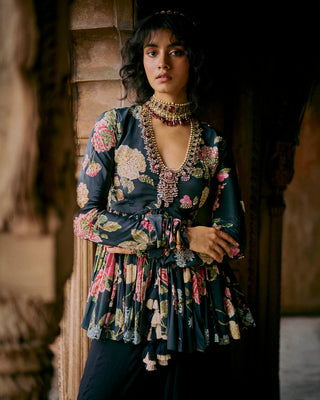 Close up look of black floral printed peplum, featuring a hand-embroidered yoke and sleeves with drawstring and tassel detailing. It is paired with solid palazzos. Perfect traditional women's wear for special occasions, cocktail parties, wedding for brides and guests. 