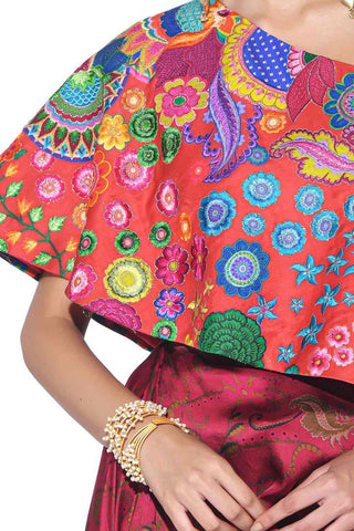 close up of crimson red one shoulder top with colorful hand embroidery.
