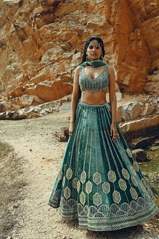 Velvet Turquoise full kali Lehenga paired with a backless heavy embroidered blouse resplendent in a gold salli, tikki & cut-daana handwork paired with a jaal bordered dupatta. Designed by Ease.
