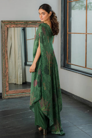 A emerald green printed one shoulder dress with coin detailing on the neck, paired with straight cut trousers.  Resort wear, brunch to soiree, vacation in style, gen-z glam. 
