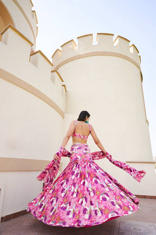 Model posing to show the back of this fuschia floral lehenga.