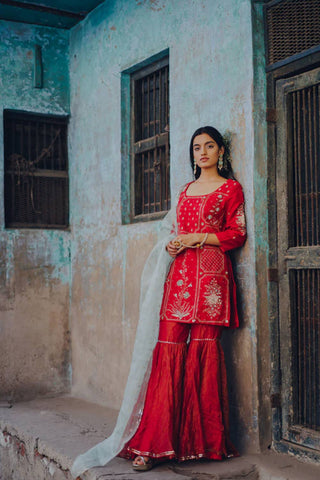 Featuring a cherry red short kurta in raw silk base with floral hand embroidery paired with matching kota doria gharara having gold zari weave. It comes with an aqua block printed dupatta in silk organza base.
Designer - Ivory By Dipika

