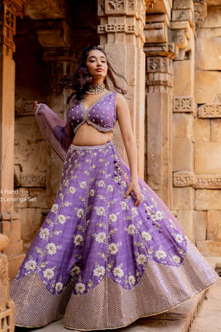 Featuring a lavender hand embroidered lehenga in silk base with chiffon floral patchwork, dori and resham embroidery with sequins and pearls. It is paired with a matching hand embroidered lavender sleeveless blouse in silk with deep V-neckline. It comes with a lavender embroidered organza dupatta. Designer- Ivory by Dipika