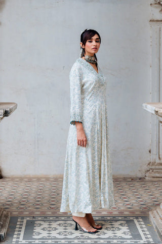 Featuring an ivory hand block floral jaal printed flared tunic in rayon base with three quarter sleeves, pockets and resham embroidered V-neckline. It comes with matching narrow pants in cotton base.