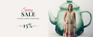 A woman wearing a cream floral Jumpuit stands to pose with promotional text on the left reading 'Spring SALE' and 'up to 15% off'. Luxury Looks Under $400. shop New In Edit.