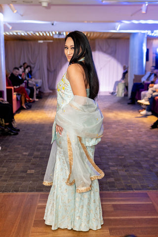 Side profile of Model posing in Powder Blue Zari Halter Kurta with Colorful Floral Embroidery, Hipster Sharara, and Organza Dupatta Set at Sydney fashion show.