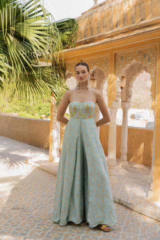 Glide into grace with our ethereal Powder Blue Zari Flap Palazzo Jumpsuit. This dreamlike creation combines the timeless elegance of a jumpsuit with the captivating flow of palazzo pants. the wide-leg palazzo pants with a delicate flap add a touch of drama. The entire jumpsuit is adorned with mesmerizing floral hand embroidery lines, creating a look that is both sophisticated and whimsical. Designed by Mona and Vishu.