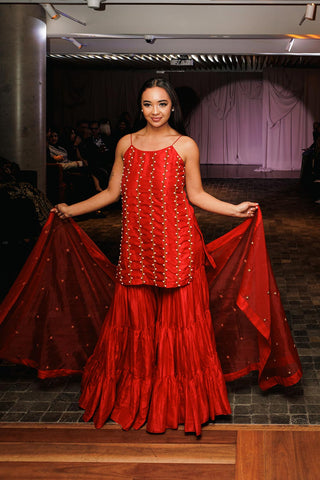 Featuring a Red Sharara Set hand embroidered with Pearl Pieces. It is paired with matching Tiered Sharara and a Dupatta. Designed by Mona and Vishu. Perfect for weddings, parties, diwali festivities and ceremonies.