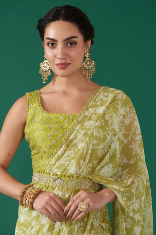 A close up look of hand embroidered blouse in silk base moss green with saree edge wrapped on the shoulder. As well a close up look of the belt.