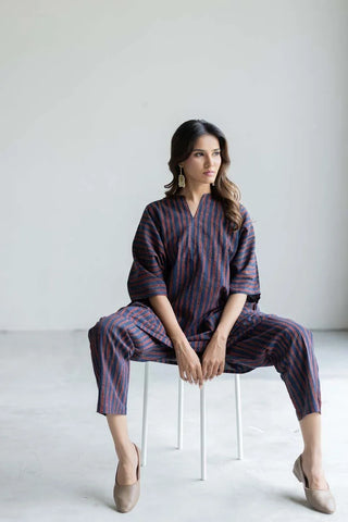Navy and rust stripe kaftan top and pant set with relaxed kimono sleeves, seated pose