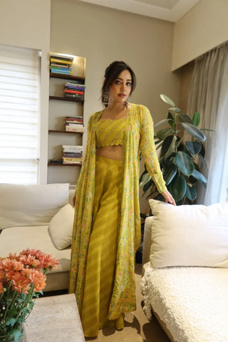 Neha Sharma models a traditional Indian indo-western outfit consisting of a yellow blouse, palazzo pant and jacket posing in modern setting environment. It is a designer Paulmi and Harsh Dress for wedding ceremonies and cocktail parties.
