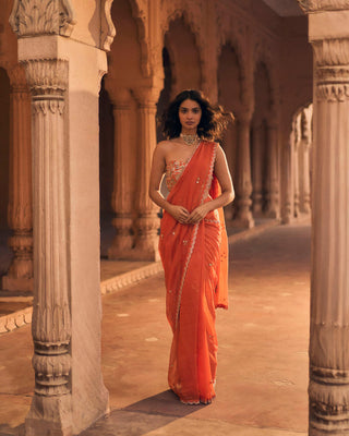 A delicate organza pre-draped saree, with hand-embroidered all-over buttis and scallops. It is paired with a corset blouse with hand embroidered chintz motifs and a criss-cross tie up on the back.