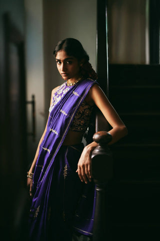 A women in a solid purple saree adorned with exquisite hand-embroidered lines and delicate floral accents. Perfect for destination wedding, festive occasions and special hosting parties