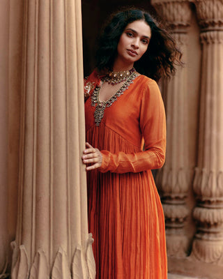 A rust orange malai chanderi gathered anarkali set, features a gathered anarkali, skirt and dupatta. The scalloped dupatta is hand-embroidered in zardozi and aari embroidery, and features signature Roop Flip bird motif, making this ensemble timeless.