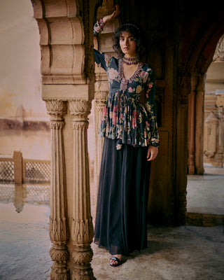 A black floral printed peplum, featuring a hand-embroidered yoke and sleeves with drawstring and tassel detailing. It is paired with solid palazzos. Designed by Paulmi and Harsh. Perfect traditional women's wear for special occasions, cocktail parties, wedding for brides and guests. 