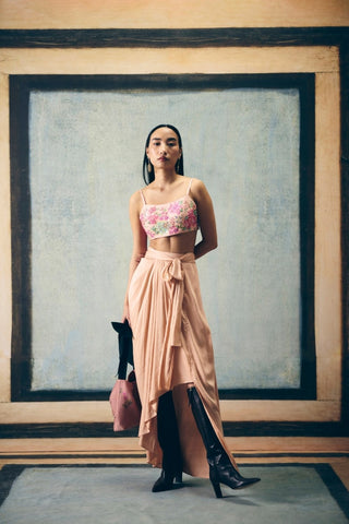 A baby pink embroidered jacket set with an asymmetric skirt and tie-up belt. It is paired with a fully embroidered bustier, adding a contemporary layer and effortless sophistication. Creating a refined designer ensemble for elegant parties, pre-wedding welcome parties. 