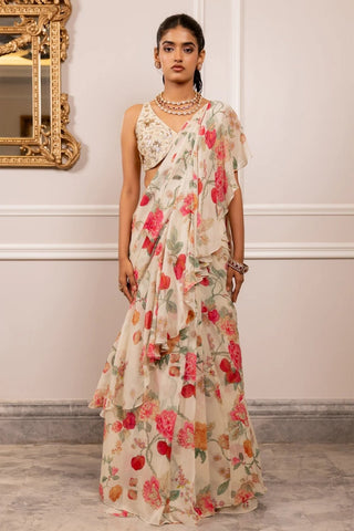 Vintage floral printed saree set is crafted in delicate georgette, offering a soft, fluid drape. Designed with layered ruffle detailing, the saree brings movement and romantic depth to the silhouette. It is paired with a sleeveless, hand-embroidered blouse, ideal for intimate weddings, festivities and sundowner events. Designed by Paulmi and Harsh.