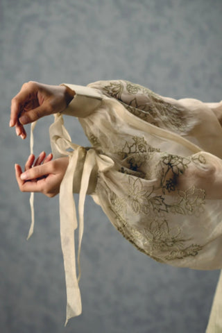 Close view of the Lili green jacket highlighting delicate threadwork embroidery and tie-up sleeve detailing, adding an airy and graceful finish to this luxury designer ensemble.