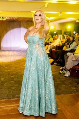 Woman in a light blue dress standing on a stage with an audience in the background. A fashionshow held at 12 Micron Barangaroo Sydney by Australian Fashion Grandeur. A perfect fusion dress for cocktail parties, wedding receiption or hens night out.