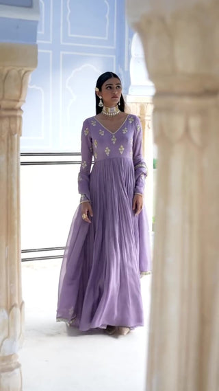Crafted for grace and grandeur, this lilac floral embroidered Anarkali with dupatta embodies refined luxury and timeless Indian tradition. Elegant lilac floral butti embroidered floor-length Anarkali with V-neckline, full sleeves, and coordinated dupatta. Designed by Ease.