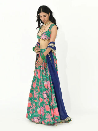 A contemporary three-piece lehenga set crafted in luxurious crepe and organza fabric in a refreshing jade green hue with multicolour accents. Featuring intricate needlework, decorative trims, and tassel embellishments, this designer ensemble blends bohemian charm with festive elegance. It is perfect for weddings, festive celebrations, and destination occasions