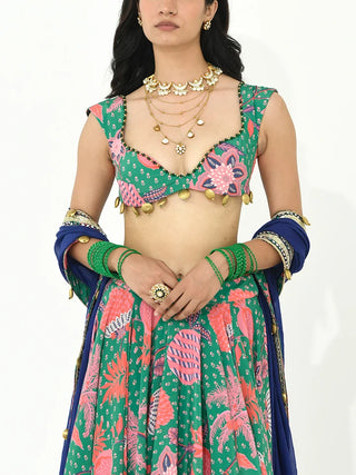 A contemporary three-piece lehenga set crafted in luxurious crepe and organza fabric in a refreshing jade green hue with multicolour accents. Featuring intricate needlework, decorative trims, and tassel embellishments, this designer ensemble blends bohemian charm with festive elegance. It is perfect for weddings, festive celebrations, and destination occasions