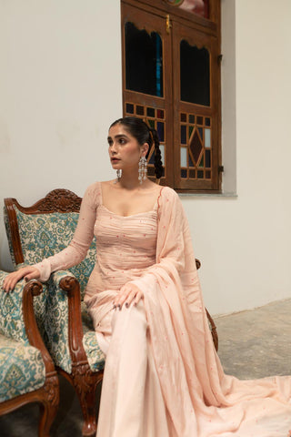 Elegant baby pink peplum sharara outfit with ruched bodice, embellished sleeves, and scallop embroidered dupatta, perfect for festive occasions.