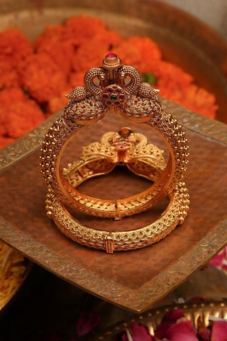 Traditional temple bangles in antique gold finish featuring detailed jadau work, pair of bangles with screw closure, ideal for weddings and cultural events.