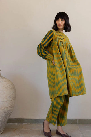 Side view of flared mustard and green striped pintuck tunic with side pocket and matching pants